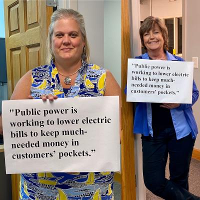 Staff holding a sign -"Public power is working to lower electric bills to keep much-needed money in customers’ pockets,” 